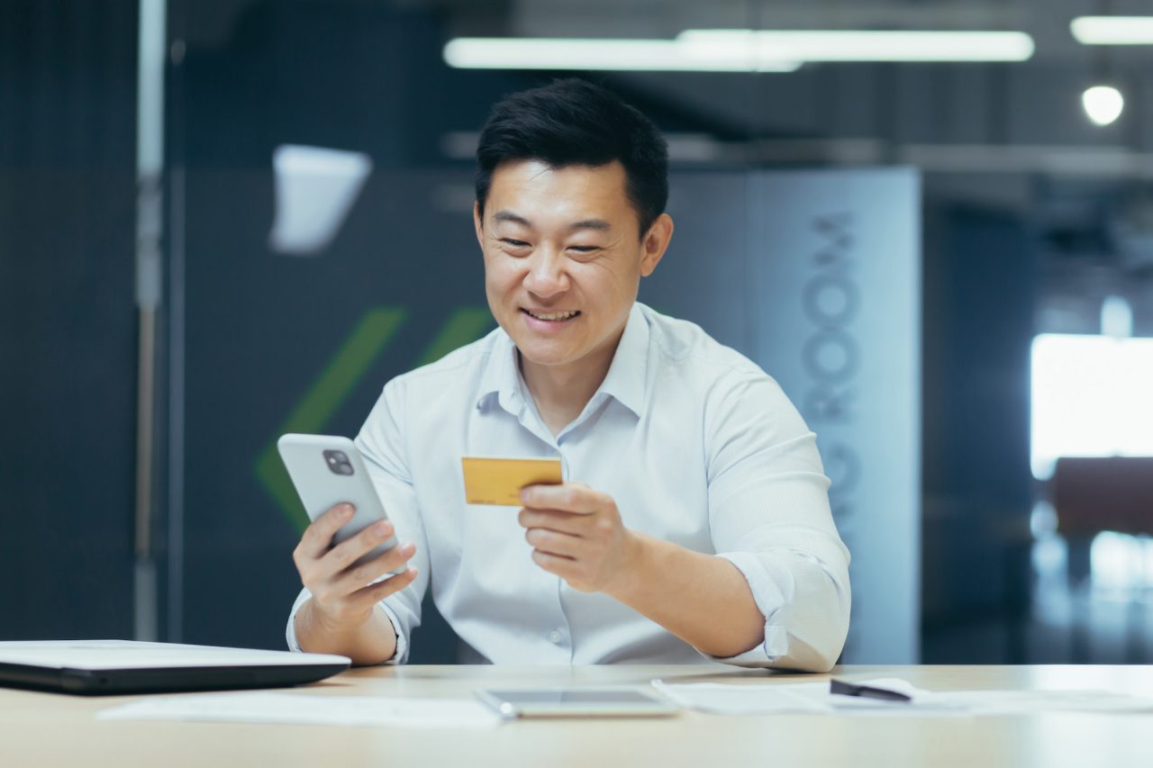 Successful Asian businessman in the office makes online purchases in an online store